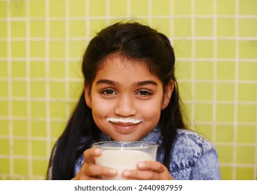 Milk moustache, smile or girl portrait in house with healthy breakfast drink on yellow wall background. Protein, dairy and face of kid in india with milkshake for balance, energy or calcium nutrition