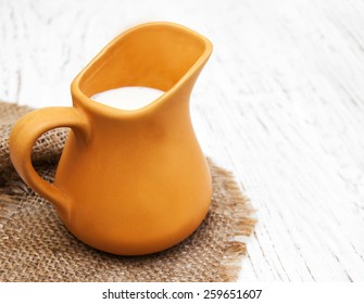 Milk In Pitcher On A Old Wooden Background