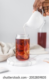 Milk Poured Into Black Tea In Glass Cup, Pouring Milk Into Cold Brew Beverage In A Can Shaped Glass