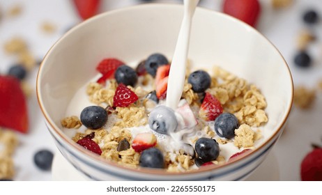 Milk pouring in bowl of healthy breakfast crunchy Granola Cereals with stawberry , blueberry vegan food, clean eating, dieting concept - Powered by Shutterstock