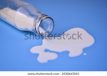 Milk is pouring out of a bottle. Spent milk on a blue background.
