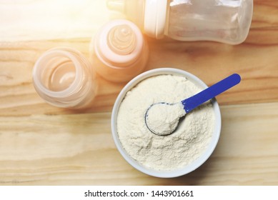 Milk Powder In Spoon With Can And Baby Bottle Milk On Wooden Table Background 