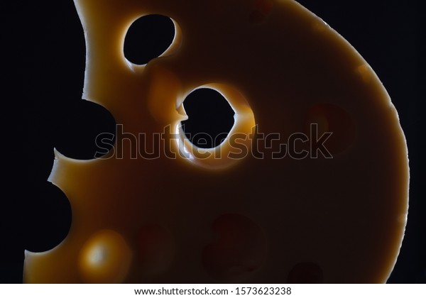 Milk product\
concept. Slice of curd cheese looking like half moon at night in\
backlight. Close up. Studio\
shot
