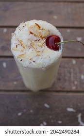 Milk Shake With Nuts And Cherry On Top Along Wooden Background