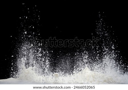 Milk splashes upward dramatically against a black background, captured in high-speed photography.