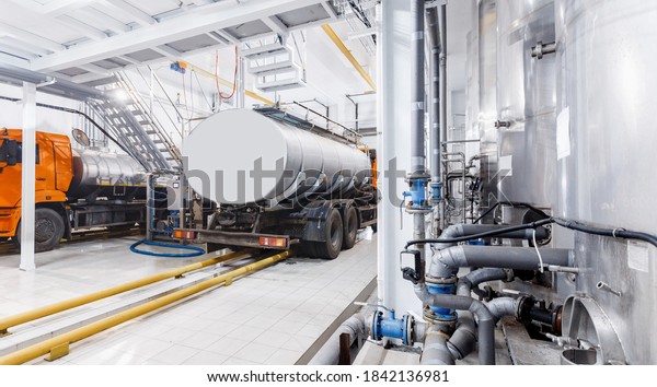 Milk tanker truck pumps products into steel\
storage tanks, dairy factory\
industry.