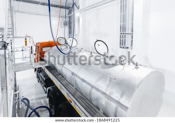 Milk tanker truck pumps products into steel\
storage tanks, dairy factory\
industry.