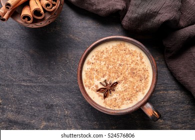 Milk tea chai latte traditional homemade refreshing morning organic healthy hot beverage drink with natural aroma spices blend in rustic clay cup on wooden table background.