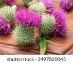 Milk thistle flower heads on wooden cutting board close up.