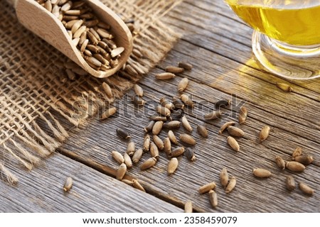 Milk thistle seeds spilled on a wooden table, with oil in the background