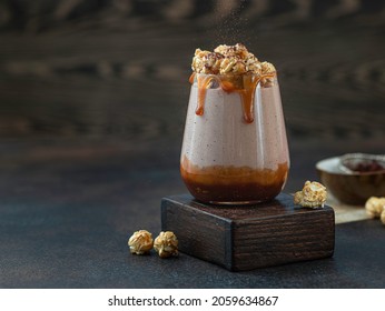 Milkshake with caramel sauce decorated by caramel popcorn and chocolate powder on green background. Copy space for text. - Shutterstock ID 2059634867