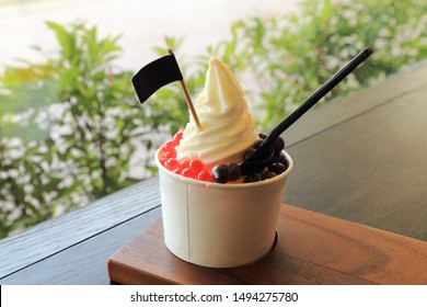 Milky Ice Cream Soft Serve In Paper Cup Topping With Chocolate Ball And Red Jelly.