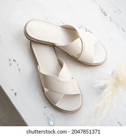 Milky leather clogs on a light abstract background.