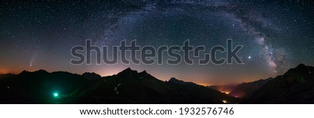 Milky Way arc and stars in night sky over the Alps. Outstanding Comet Neowise glowing at the horizon on the left. Panoramic view, astro photography, stargazing.