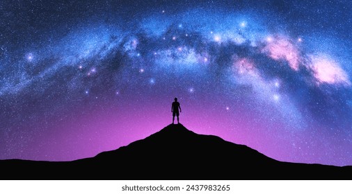 Milky Way arch and man on the mountain peak at starry night. Silhouette of alone guy, pink sky with bright stars in summer. Galaxy. Space background. Landscape with arched milky way. Travel and nature - Powered by Shutterstock