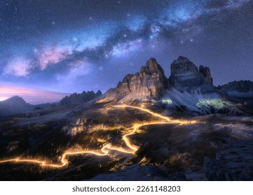 Milky Way, car light trails on mountain road, high rocks at starry night in summer. Tre cime, Dolomites, Italy. Colorful landscape with blurred light trails, hills, mountain peaks, sky with stars - Powered by Shutterstock