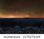 Milky Way core rising horizontally on horizon from mountain edge and above a grand valley