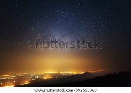 Milky way galaxy and city light at Phutabberk Phetchabun in Thailand.Long exposure photograph.With grain