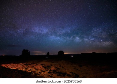 The Milky Way and night sky rises above Monument Valley in Arizona.
