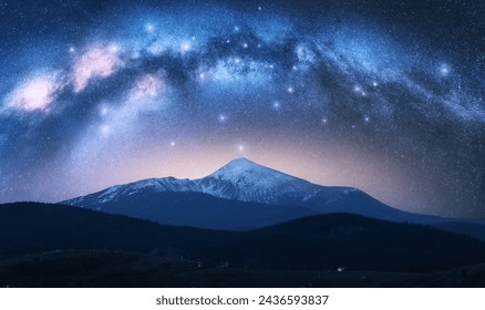 Milky Way over the beautiful Goverla mountain with snow covered peak at night in summer in Ukraine. Colorful landscape with bright starry sky with Milky Way arch, snowy rocks, hills. Space. Nature  - Powered by Shutterstock