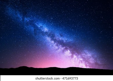 Milky Way and pink light at mountains. Night colorful landscape. Starry sky with hills at summer. Beautiful Universe. Space background with galaxy. Travel background - Shutterstock ID 471693773