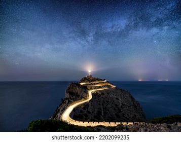 Milky way rising over an illuminated road with light trails at the Far de Formentor lighthouse on the island of Mallorca, Spain - Shutterstock ID 2202099235