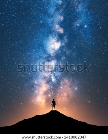 Milky Way and sporty man on mountain peak at starry night. Silhouette of a guy on the hill, sky with stars, yellow light in Nepal. Galaxy. Space landscape with bright milky way. Travel background