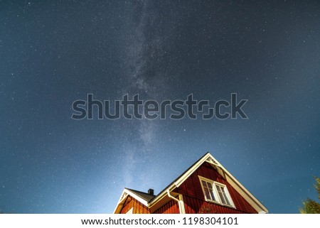 milky way stars at blue sky right above red swedish wooden house and apple tree in the garden at end of summer, autumn, Västerbotten,  West Bothnia province, north of Sweden