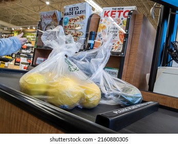 Mill Creek, WA USA - circa April 2022: Angled view of a customer placing bagged produce on a conveyor belt to be purchased inside a Town and Country grocery store.