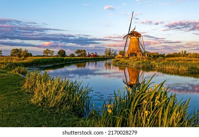 Mill on the bank of the village river. Windmill at village river. Windmill at river. River mill
