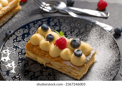 Millefeuille cake. Dessert millefeuille of puff pastry layered with custard cream, raspberries, blueberries. Photo for advertising confectionery products. Close-up