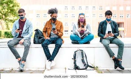 Millenial friends using smart phones with face mask on Covid second wave - Worried guys and girls watching news on mobile smartphone - College students sitting at university break