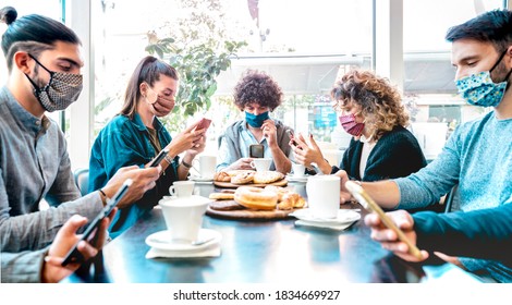 Millenial People Using Mobile Smart Phones At Coffee Bar - New Normal Lifestyle Concept With Friends Checking Contact Tracing App During Pandemic Second Wave - Bright Filter With Focus On Central Guy