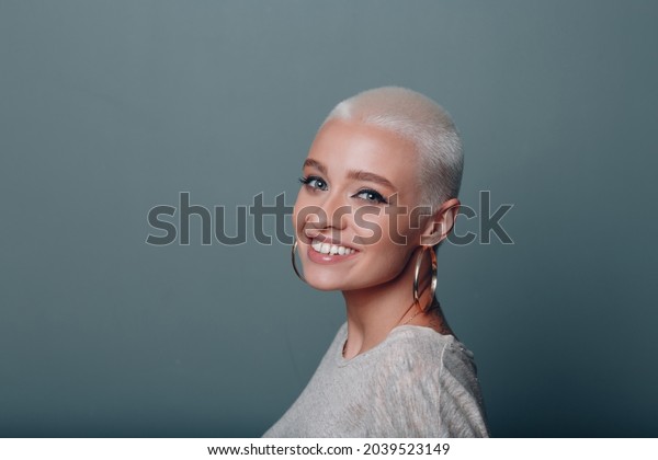 Millenial young european woman with short blonde\
hair smiling portrait
