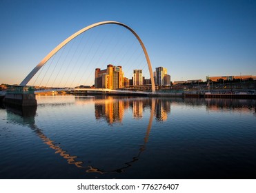 Millenium Bridge on Newcastle Quayside illuminated by the evening sun and reflected in the river Tyne