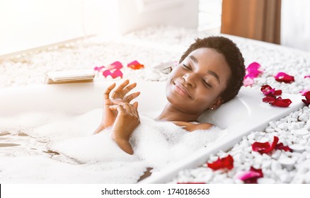 Millennial african american girl relaxing in bathroom with foam, sun flare