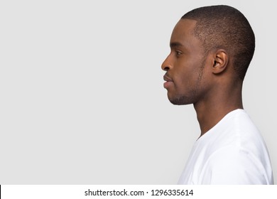 Millennial african american man standing in profile isolated on blank white grey studio background, confident black guy looking forward at copy space thinking of future leadership, side view portrait