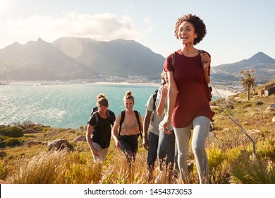 Millennial African American woman leading friends on an uphill hike by the coast, close up - Powered by Shutterstock