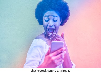 Millennial African Woman Smiling And Using Smart Mobile Phone - Black Afro Girl Having Fun In Front Of Cell Camera - Focus On Face - Youth Lifestyle Concept - Radial Blue And Purple Filter Editing