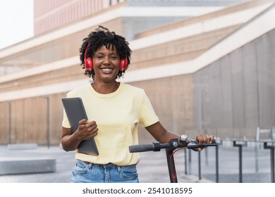 Millennial afro woman standing with electric scooter listening music - Powered by Shutterstock