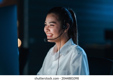 Millennial Asia young call center team or customer support service executive using computer and microphone headset working technical support in late night office. Telemarketing or sales job concept. - Powered by Shutterstock