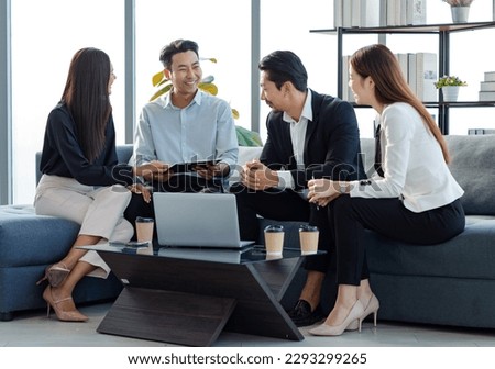 Millennial Asian professional successful businessman in formal suit sitting with female secretary with clients after job negotitation acheivement agreement in company office living room.