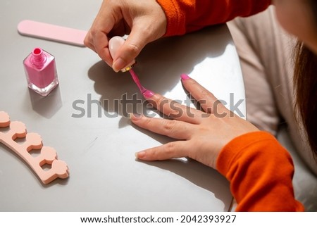 Millennial Asian woman friends sitting on the floor in living room and applying nail polish together. Female friendship enjoy weekend activity lifestyle with beauty treatment and make up at home