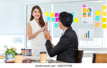 Millennial Asian young professional businesswoman presenter standing talking presenting company business model data report on glass board to male and female employee colleagues in office meeting room. - Shutterstock ID 2205747783