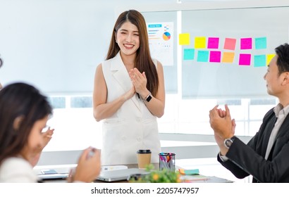 Millennial Asian young professional businesswoman presenter standing talking presenting company business model data report on glass board to male and female employee colleagues in office meeting room. - Shutterstock ID 2205747957