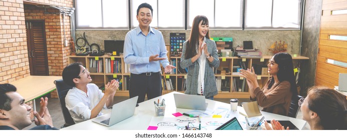 Millennial Boss Team Leader Introducing New Asian Woman Employee To Colleagues In Creative Office Workplace. Welcoming Hired Newcomer Member To Team. First Work Day Get Clapping Hands With Colleagues.