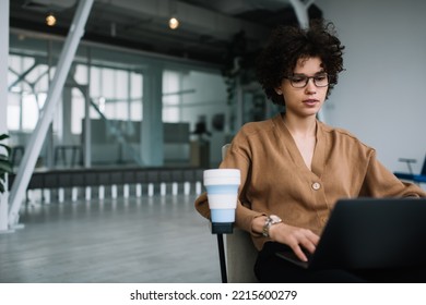 Millennial Caucasian Businesswoman Typing On Laptop Computer During Work. Concept Of Modern Successful Woman. Young Focused Curly Girl In Glasses Sitting In Armchair In Open Space Office