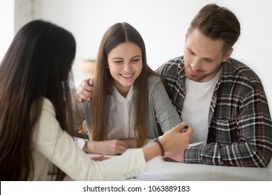 Millennial Couple Considering Mortgage Investment Loan, Planning Wedding At Meeting With Financial Advisor Realtor Planner, Young Smiling Clients Customers Thinking Of Buying Real Estate Or Insurance