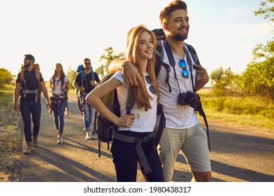 Millennial Couple Hiking Together With Their Friends In Countryside, Copy Space. Happy Backpackers Traveling In Wilderness At Summertime