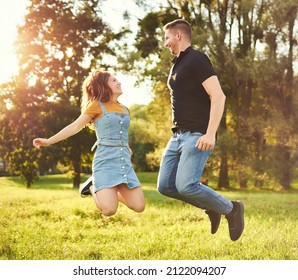Millennial couple jumping together outdoors in a park - Happy people lifestyle concept
